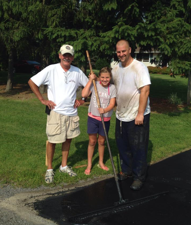 Todd Esposito, his daughter, and family member sealing a driveway