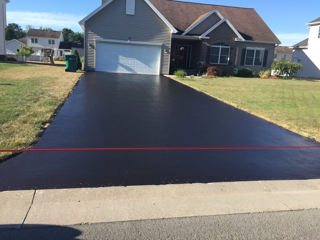Half-sealed driveway showing dramatic before-and-after contrast in Rochester NY