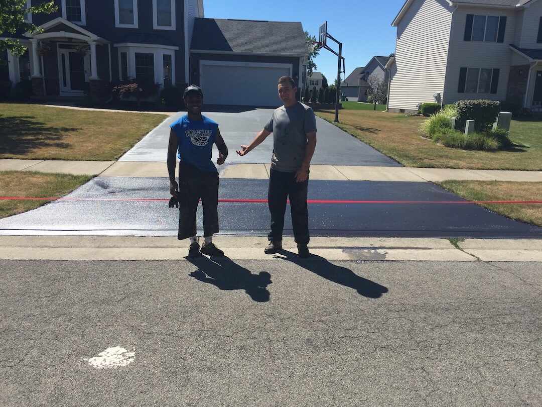 Crew with a finished sealed driveway, half-applied detail