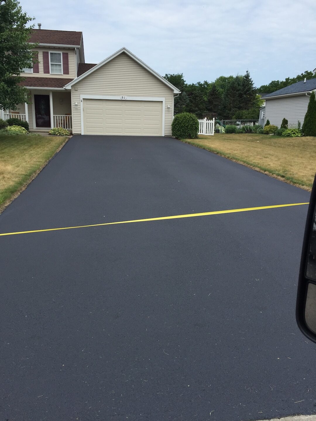 Wide sealed driveway leading to a large home